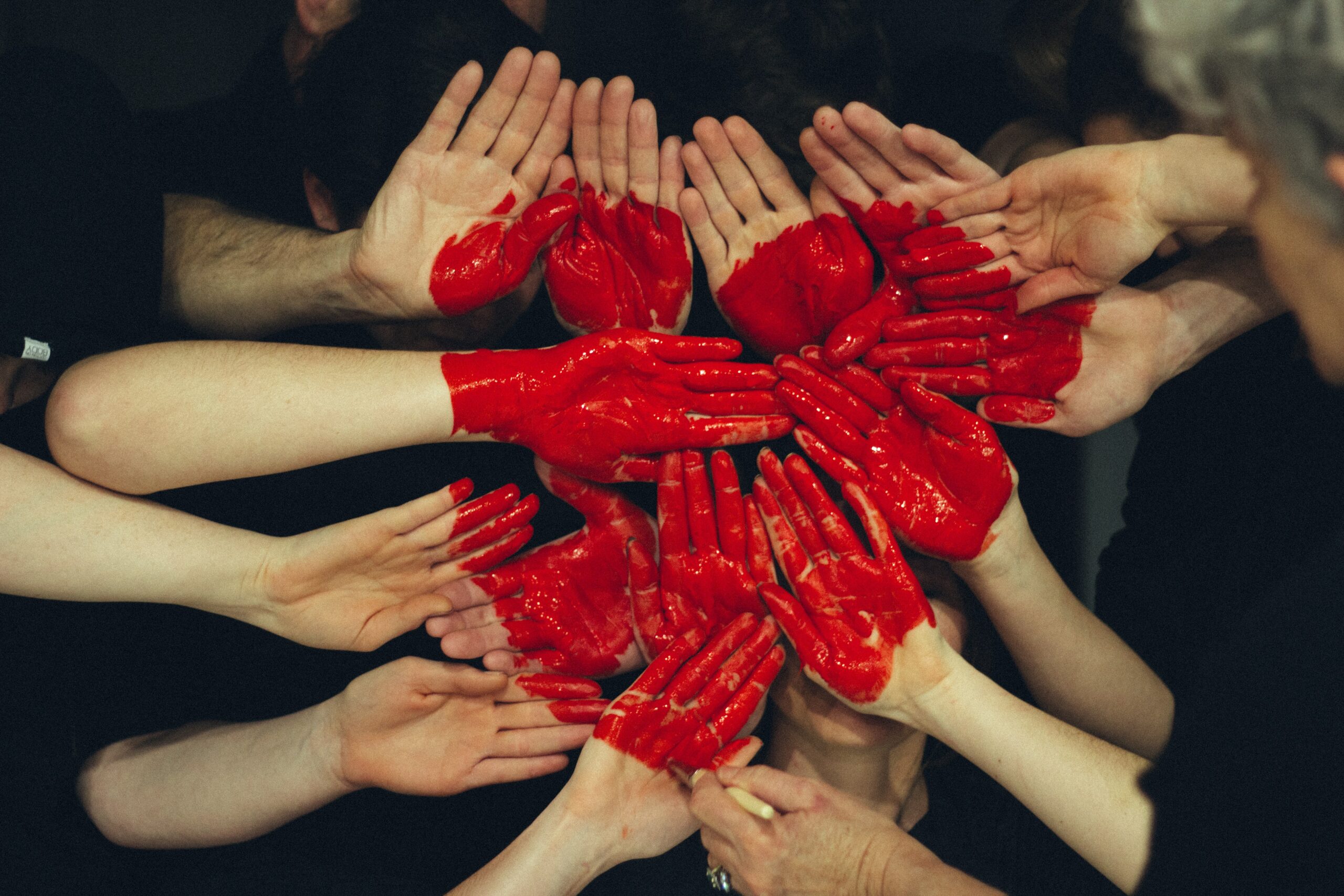 Image de plusieurs mains rassemblées dont les paumes sont peintes en rouge pour représenter un coeur